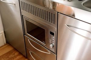 a microwave oven sitting next to a stainless steel refrigerator at The Rectory Rooms, Studio 1 in Skipton