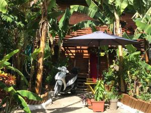 Chambre1 Résidence Beauregard في Koungou: سكوتر متوقف أمام منزل مع مظلة