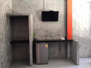 a room with a television on a shelf and a refrigerator at Janrawee Resort in Ban Phang Kan Nua