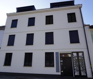 a white building with black windows and a door at Das Stadthouse in Grieskirchen
