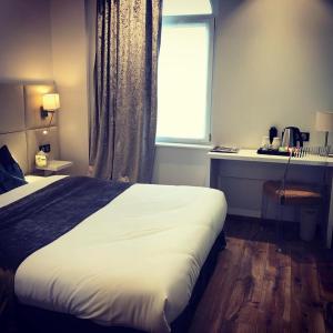 a bedroom with a large bed and a window at Hôtel de la Paix in Bapaume