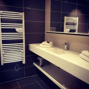 ein Badezimmer mit einem Waschbecken, einem Spiegel und Handtüchern in der Unterkunft Hôtel de la Paix in Bapaume