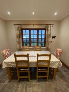 comedor con mesa, sillas y ventana en Carrick Beg Self Catering Holiday Accommodation with Hot Tub en Sulby