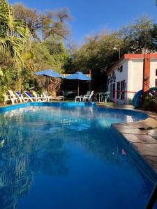 ein großer blauer Pool mit Stühlen und Sonnenschirmen in der Unterkunft Hotel Bristol in Termas de Río Hondo