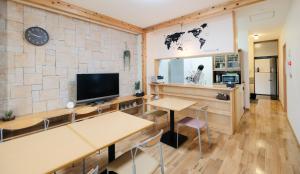 Habitación con mesas, TV y pared. en Tottori Guest House Miraie BASE en Tottori
