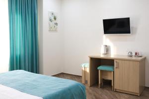 a hotel room with a bed and a desk with a television at Timashevsk Rich Hotel in Timashevsk