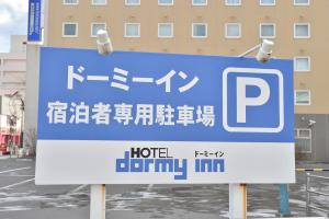 a sign for a hotelenny inn in a parking lot at Dormy Inn Tomakomai in Tomakomai