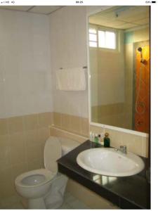 une salle de bain avec un lavabo, des toilettes et un miroir dans l'établissement BM Mansion, à Bangna