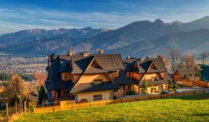 a house on a hill with mountains in the background at Butorowy Dwór in Kościelisko