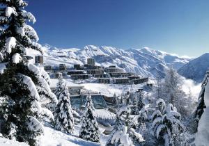 una montaña cubierta de nieve con un complejo en la distancia en Studio Queyrelet 1 pied des pistes avec balcon & vue 2-4 personnes, en Orcières