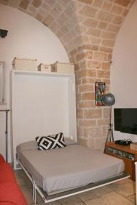 バーリにあるLa casa nel vicoloのレンガの壁のある部屋にあるベッド