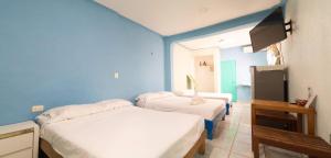Cette chambre bleue comprend 2 lits et une télévision. dans l'établissement Posada Paso Del Sol, à Isla Mujeres