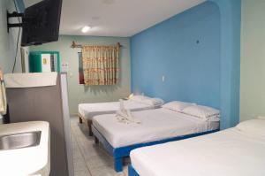une chambre à l'hôpital avec 3 lits et un lavabo dans l'établissement Posada Paso Del Sol, à Isla Mujeres