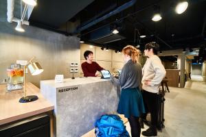 three people standing at a counter in a kitchen at &AND HOSTEL SHINSAIBASHI EAST in Osaka