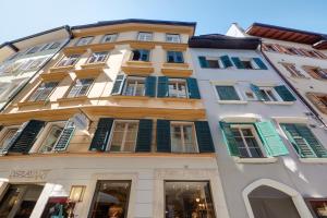 ボルツァーノにあるFranciscus Apartmentsの緑のシャッター付き窓がある白い高い建物