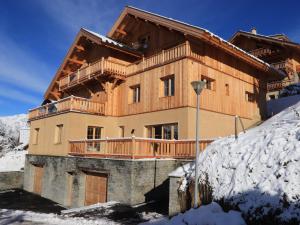 een groot gebouw met een balkon in de sneeuw bij Chalet l'Ardoisière in Villard-Reculas
