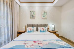 a bedroom with a large bed with blue and pink pillows at 拈花湾景区内花园庭院别墅套房---购票入住 in Wuxi