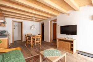 a living room with a table and a television at Casa Piccolin in Falcade
