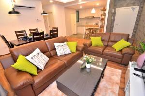 sala de estar con sofá marrón y almohadas amarillas en Kuching City Luxury Vivacity Suite A2, en Kuching