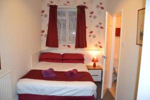 Un dormitorio con una cama con dos sombreros morados. en Chiswick Lodge Hotel en Londres