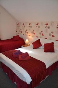 Chiswick Lodge Hotel في لندن: سريرين في غرفة الفندق عليها وسائد حمراء