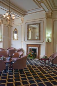 a waiting room with chairs and a mirror and a fireplace at Prince Of Wales Hotel in Southport