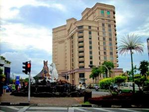 a large building with a statue in front of it at New Riverbank Suites - Waterfront Kuching City in Kuching