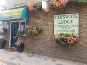 un edificio in mattoni con un cartello e fiori di Chiswick Lodge Hotel a Londra