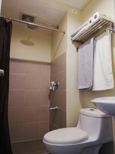 a bathroom with a toilet and a shower and a sink at Cozy on the 28th! IT Park Cebu City in Cebu City