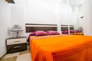 a bedroom with a bed with an orange blanket and purple pillows at Cubo's Apartamento 2 Concha del Mar in Fuengirola