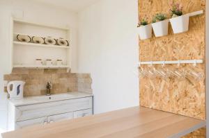 Designed Studio Apartment في Kefar Weradim: مطبخ مع حوض ومكتب مع أكواب على الحائط