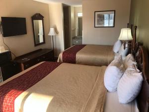 a hotel room with two beds with people laying on them at Motor Inns Of America in Madisonville