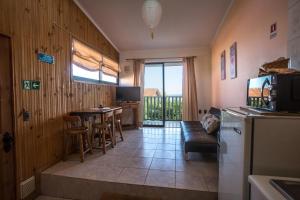 eine Küche und ein Wohnzimmer mit einem Tisch und einem Sofa in der Unterkunft Cabañas Piedra Grande in Pichilemu