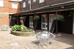 un groupe de chaises assis à l'extérieur d'un bâtiment dans l'établissement Russ Hill Hotel, à Charlwood