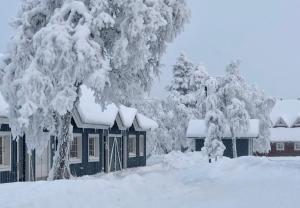 a house covered in snow next to some trees at Herranterttu Apartments in Saariselka