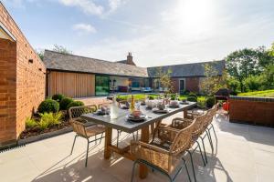 y un patio con mesa de comedor y sillas. en The Barn : Luxury Indoor/Outdoor Countryside Bliss, en Clipston