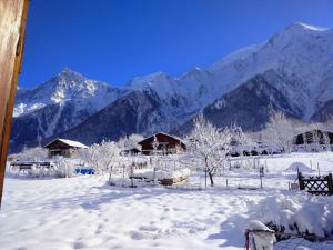 a snow covered field with houses and mountains at Chalet Le Marmouzet in Les Houches
