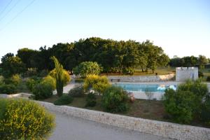 un jardín con piscina y pared de piedra en B&B Corte Del Camedrio en Cisternino