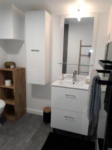 uma casa de banho branca com um lavatório e um espelho em La perle du 58 - T2 Parking Wifi Terrasse CLIM em Rodez