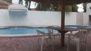 a table and chairs next to a swimming pool at Hotel Albatros Palace in Manzanillo