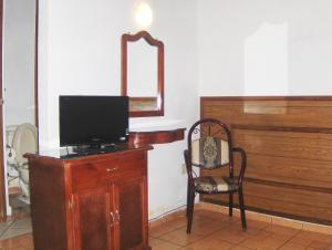 a room with a tv and a chair and a mirror at Hotel Albatros in Manzanillo