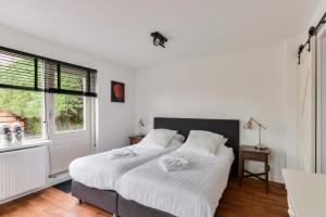 1 dormitorio con 1 cama con sábanas blancas y ventana en Luxury Garden View Apartment, en Zandvoort