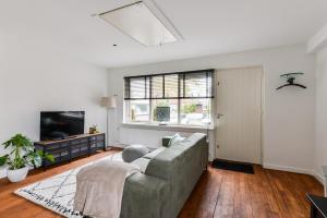 sala de estar con sofá y TV en Luxury Garden View Apartment, en Zandvoort