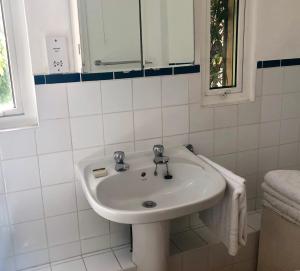 ein weißes Badezimmer mit einem Waschbecken und einem Spiegel in der Unterkunft Lauras Townhouse Apartments Erte's Atelier in Bath