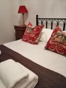 Una cama con almohadas rojas y toallas blancas. en Crown Spa Apartment 13 en Scarborough