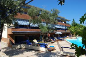 a hotel with a swimming pool and chairs next to a building at Philoxenia Village Hotel-Studios in Pefkochori