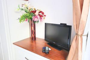 un televisor sentado en una mesa con un jarrón de flores en Whitburn Guest House About 7 mins Walk To The City Free Internet TV en Doncaster