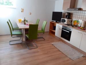 cocina con mesa de comedor y sillas verdes en Souterrain Apartment Laatzen, en Hannover