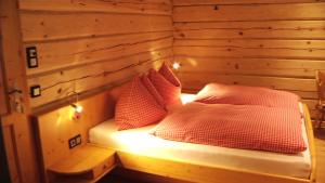 a bed in a wooden room with two pillows at Alpenchalets Weissenbacher in Tamsweg