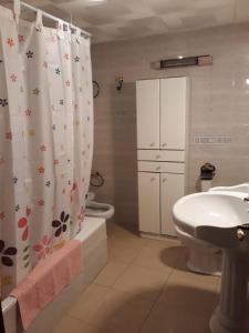 Un baño con lavabo, inodoro y cortina de ducha. en Casa Gazquez, en Santo Tomé